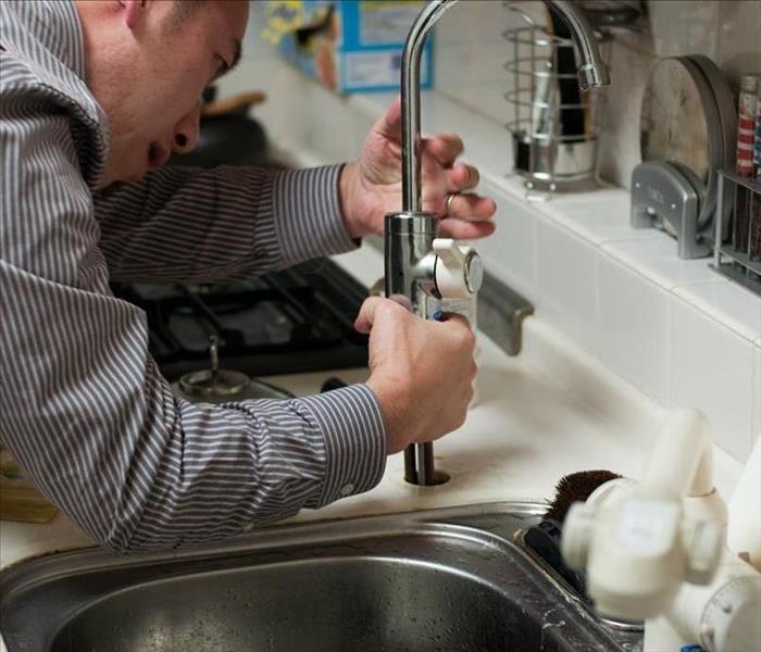 Contractor fixing a sink faucet in the kitchen.